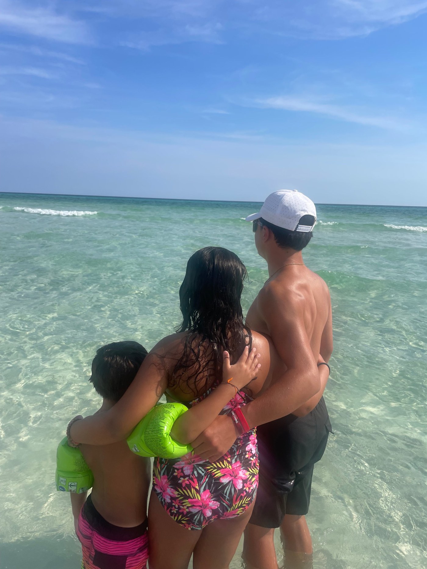 Natalie's three kids hugging at the beach, facing the ocean